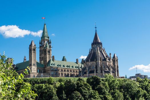 Houses of Parliament of Canada stands on a mountain covered with trees, over a river