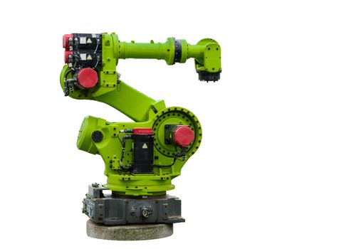The old, industrial robot, painted in green, stands on  a concrete pedestal