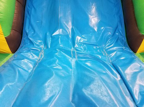 worn or weathered or damaged plastic or rubber blue slide on bounce house