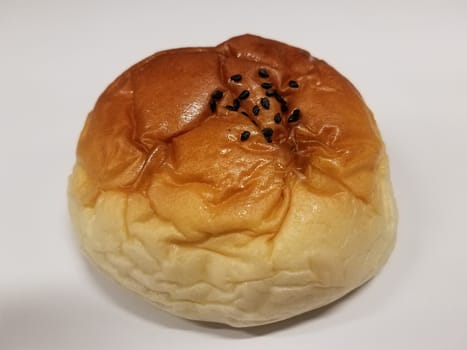 bread or bun baked food with black seeds on white surface or table