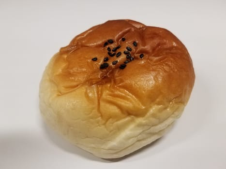 bread or bun baked food with black seeds on white surface or table