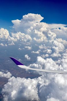 View from airplane window on the wing  over the white cloud and blue sky in the sunny day.