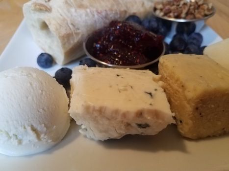 cheese pecans and bread and blueberries with jam on white plate