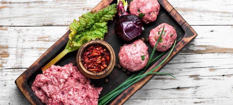 Raw beef meatballs with spices on rustic background