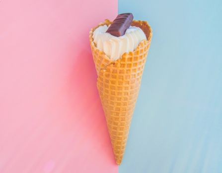 Vanilla ice cream cone with chocolate on a background of pastel colors pink and blue.