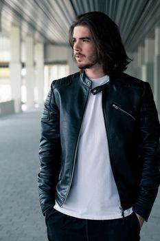 Half length portrait of handsome bearded man dressed in fashionable clothes standing on street against while wall background with area for advertising content. Handsome hipster guy posing on copy space