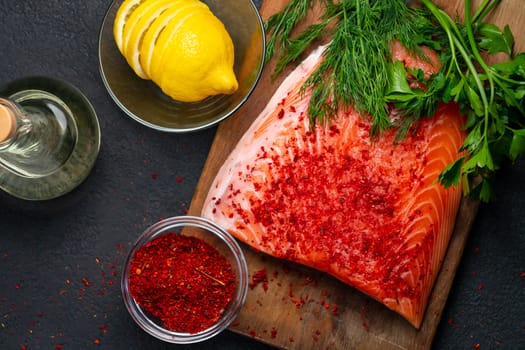 Piece of salmon fillet on a wooden cutting board with ingredients for its further preparation, top view - photo, image.