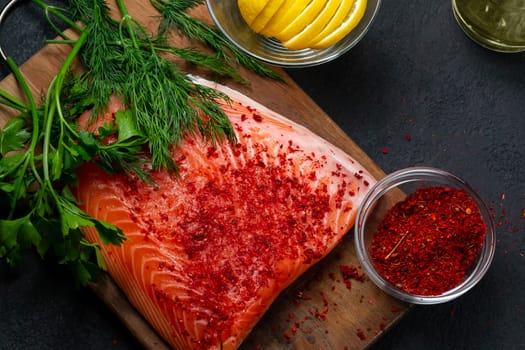 Piece of salmon fillet on a wooden cutting board with ingredients for its further preparation, top view - photo, image.