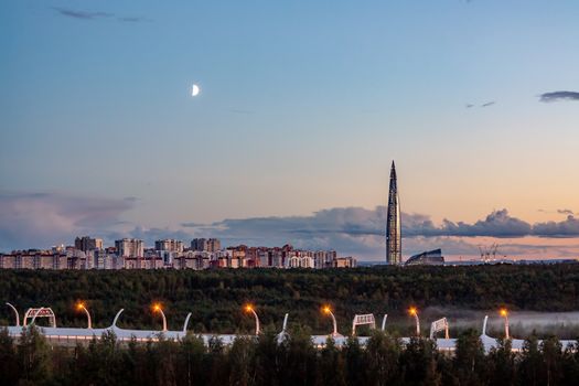 Evening cityscape. View of the Lakhta Center tower in St. Petersburg in the sunset with clouds and moon.