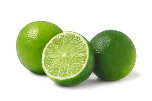 Fresh ripe limes, two whole and one half isolated on white background with shadow - image.