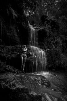 A shimmering waterfall rushed over her.  Standing on slippery rocks wet from the cascades the woman let the falling water invigorate herskin before taking a swim in a secluded waterhole in bushland Australia