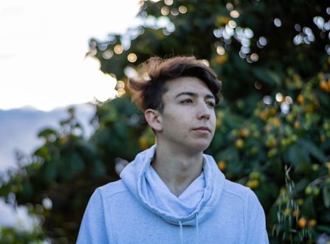 Young boy posing with a tree in the background