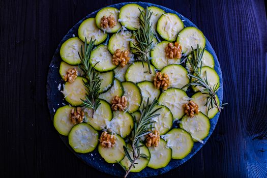 Carpaccio of zucchini with nuts and cheese on dark wooden background