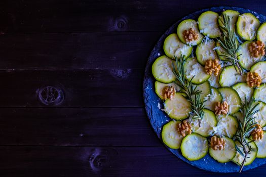 Carpaccio of zucchini with nuts and cheese on dark wooden background