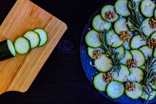 Carpaccio of zucchini with nuts and cheese on dark wooden background