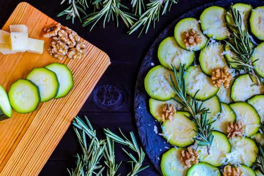 Carpaccio of zucchini with nuts and cheese on dark wooden background