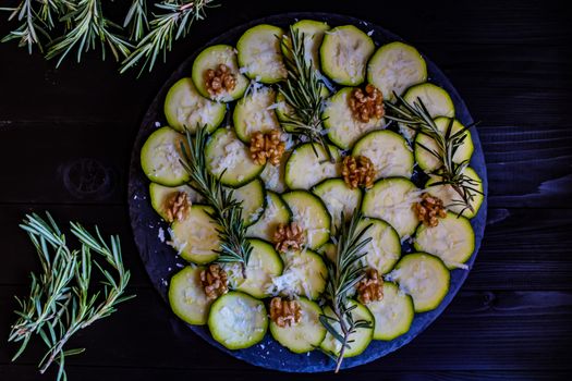 Carpaccio of zucchini with nuts and cheese on dark wooden background