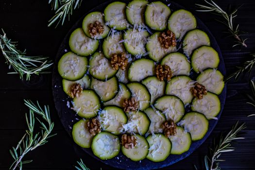 Carpaccio of zucchini with nuts and cheese on dark wooden background