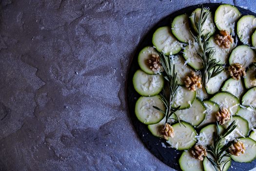 Carpaccio of zucchini with nuts and cheese on gray background