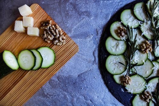 Carpaccio of zucchini with nuts and cheese on gray background