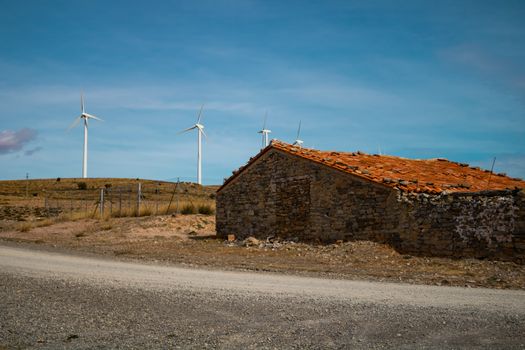 Old abandoned stone house with windmills in the background