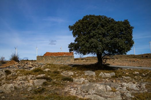 Old abandoned stone house with windmills in the background
