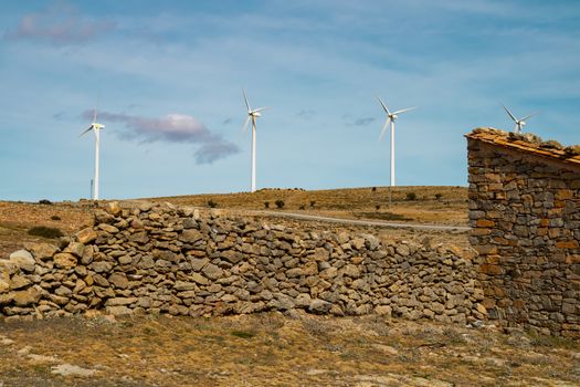 Old abandoned stone house with windmills in the background