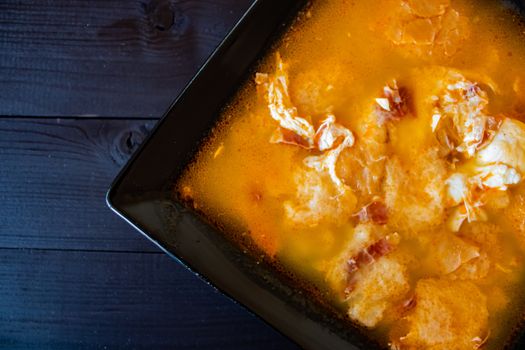 Typical Spanish garlic soups in composition on dark wood background