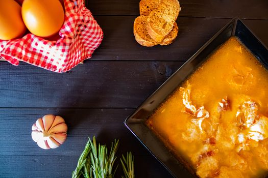 Typical Spanish garlic soups in composition on dark wood background