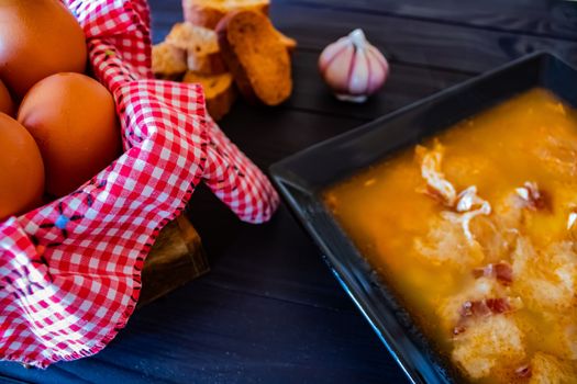 Typical Spanish garlic soups in composition on dark wood background