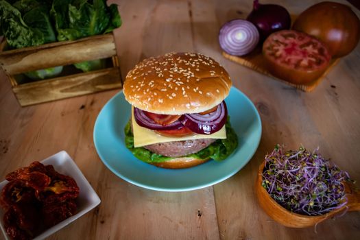 Hamburger and ingredients in composition on wooden background