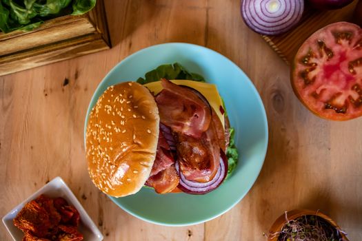 Hamburger and ingredients in composition on wooden background
