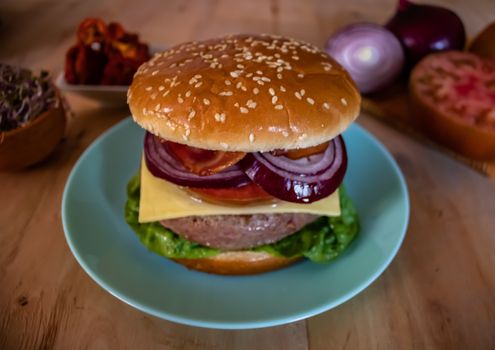 Hamburger and ingredients in composition on wooden background