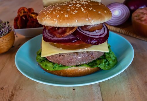 Hamburger and ingredients in composition on wooden background