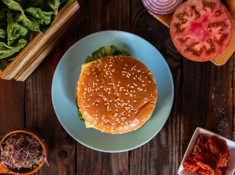 Hamburger and ingredients in composition on wooden background