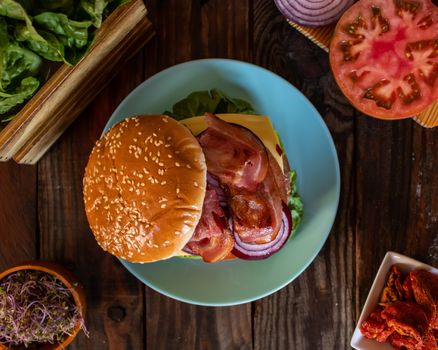 Hamburger and ingredients in composition on wooden background