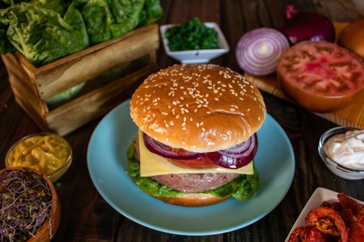 Hamburger and ingredients in composition on wooden background
