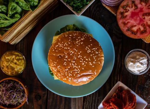 Hamburger and ingredients in composition on wooden background
