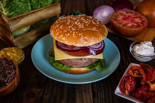 Hamburger and ingredients in composition on wooden background