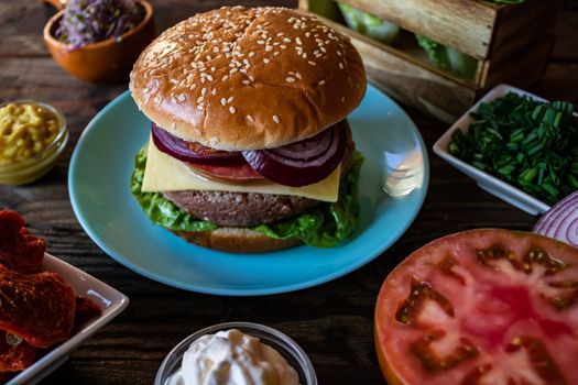 Hamburger and ingredients in composition on wooden background