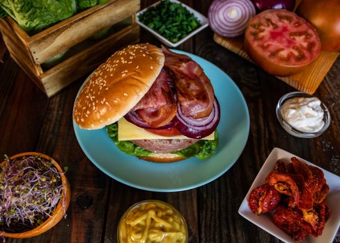 Hamburger and ingredients in composition on wooden background