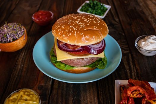 Hamburger and ingredients in composition on wooden background