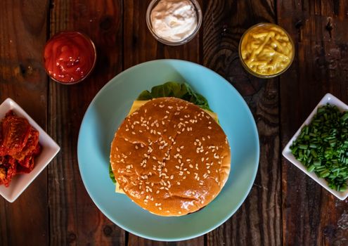 Hamburger and ingredients in composition on wooden background