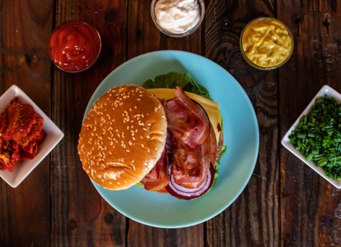 Hamburger and ingredients in composition on wooden background