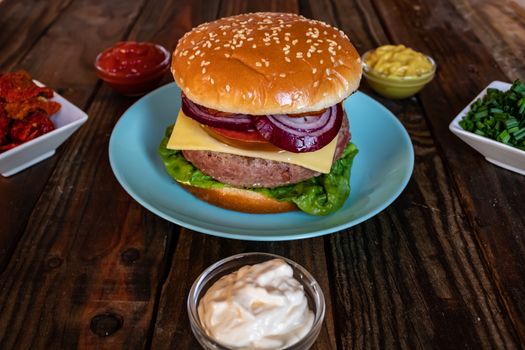 Hamburger and ingredients in composition on wooden background