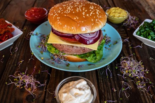 Hamburger and ingredients in composition on wooden background
