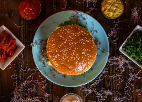 Hamburger and ingredients in composition on wooden background
