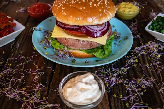 Hamburger and ingredients in composition on wooden background