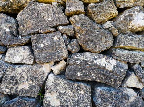 Wall of gray interspersed stones made by hand mind