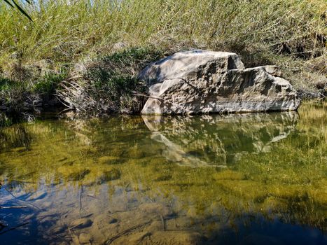 Large rock reflected in the waters of the Palancia river